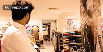 a man is looking at a painting of a woman in a clothing store .