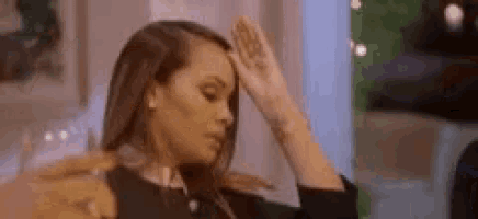 a woman is sitting on a couch with her hand on her head .