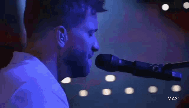 a man singing into a microphone with a ma21 watermark on the bottom