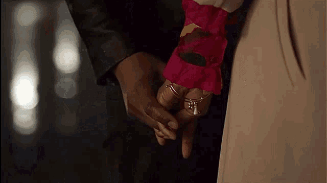 a man and a woman are holding hands and the woman has a ring on her finger