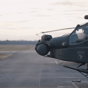 a military helicopter is sitting on a runway with the army logo on the side .