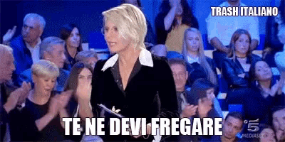 a woman is standing in front of a crowd of people and saying te ne devi fregare .