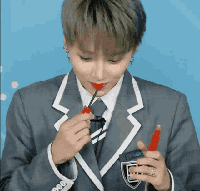 a man in a suit and tie is applying lipstick