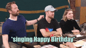 a group of people singing happy birthday while sitting around a table