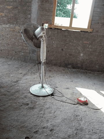 a fan is attached to a brick wall with a cord hanging from it