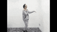 a man is dancing in a room with a white wall and a carpet .