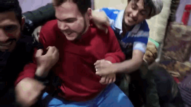 a man in a red sweater is being held by two men
