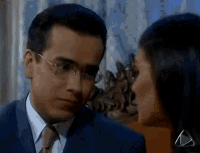 a man in a suit and tie is looking at a woman in a black dress
