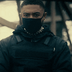 a man wearing a black mask and a black jacket looks at the camera