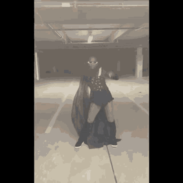 a woman is standing in a parking garage wearing a cape .