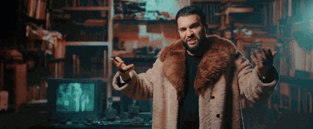 a man wearing a fur coat is standing in front of a television