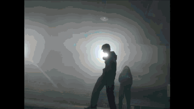 a man and a woman are standing in a dark room with a light shining on them