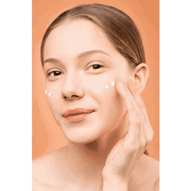 a woman is applying lotion to her face