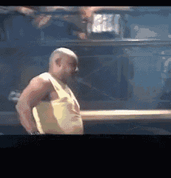 a bald man in a yellow tank top is standing in front of a car .
