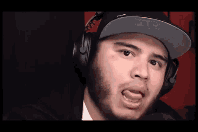 a man wearing headphones and a hat is sticking his tongue out .