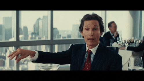 a man in a suit and tie is pointing to something