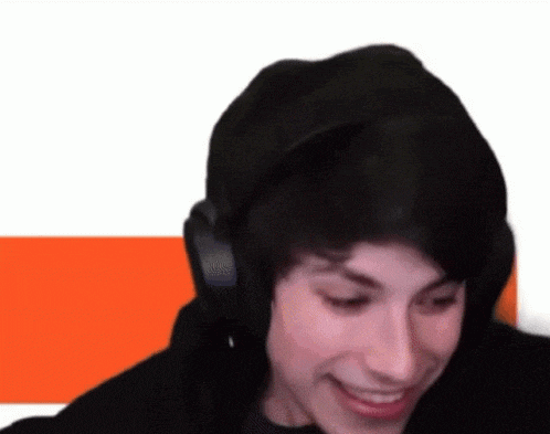 a young man wearing headphones is smiling while looking at the camera .