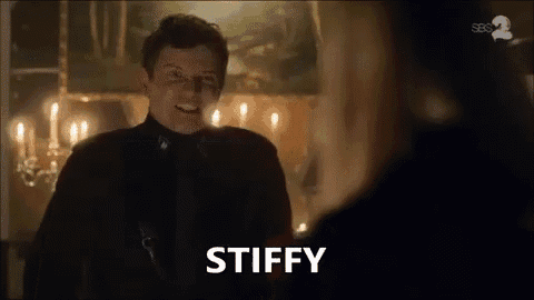 a man in a black suit is talking to a woman in a room with candles .