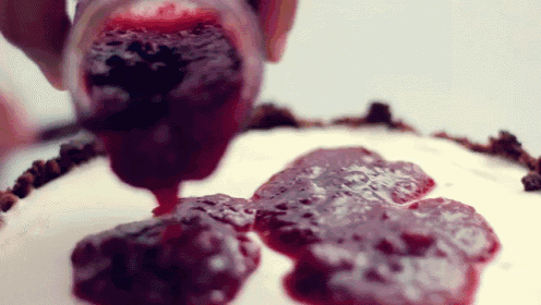 a person is pouring raspberry jam onto a cake .