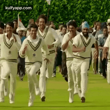 a group of men in white shirts are running on a field .