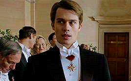 a man in a tuxedo with a medal around his neck stands in front of a group of people