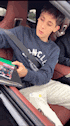 a young boy is sitting in the back seat of a car holding a green box .