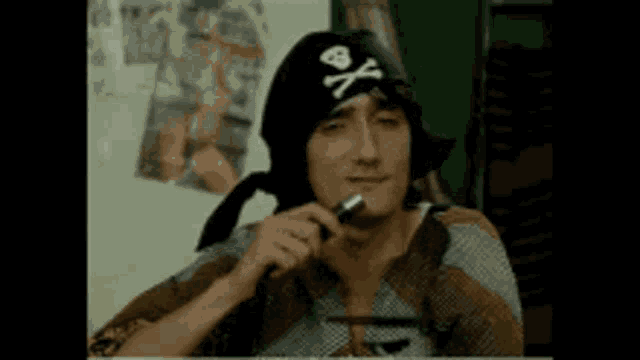 a man is wearing a pirate hat and smoking a cigarette .