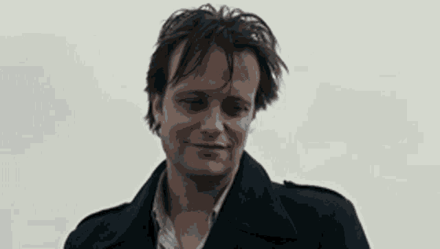 a man wearing a blue jacket is smiling and looking at the camera