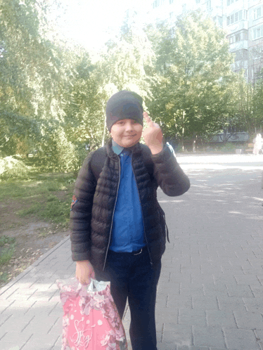 a boy wearing a black jacket and a blue shirt is holding a pink bag with the word swag on it