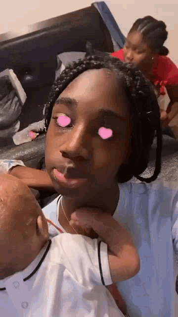 a woman is holding a baby in her arms with pink hearts in her eyes .