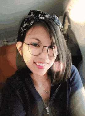 a girl wearing glasses and a headband is smiling
