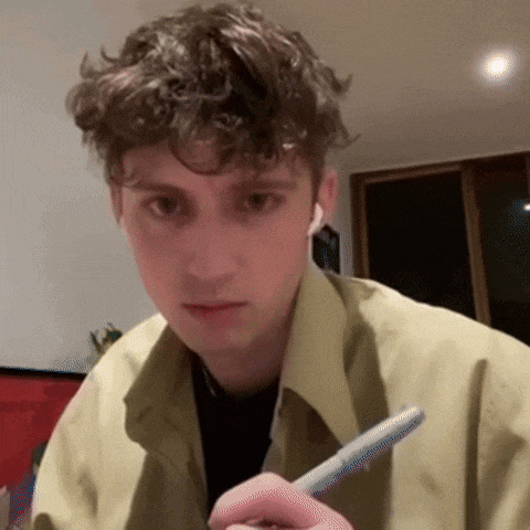 a young man with curly hair is holding a pen in his right hand