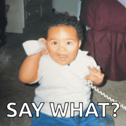 a baby talking on a telephone with the words say what below him