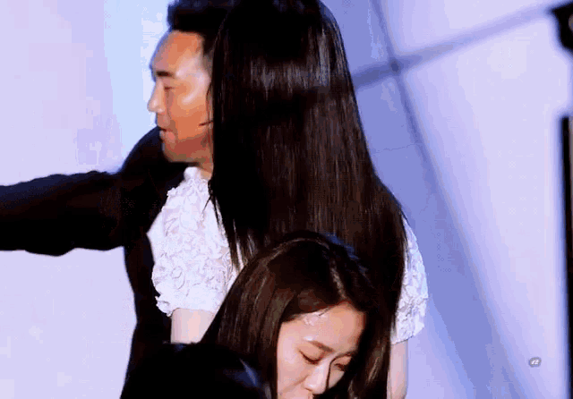 a woman with long black hair is being held by a man in a black suit