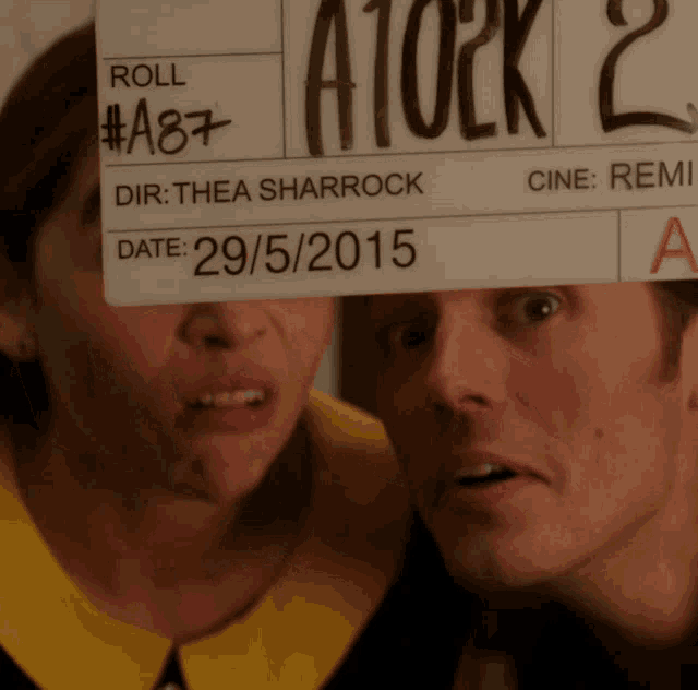 a man and a woman holding a sign that says roll # a87 dir thea sharrock date 29/05/2015