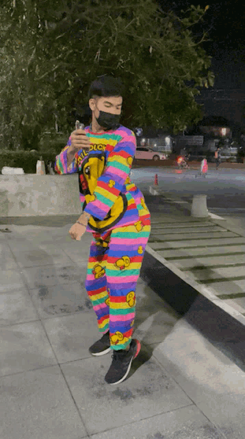 a man wearing a mask and a colorful outfit with a duck on it is standing on a sidewalk