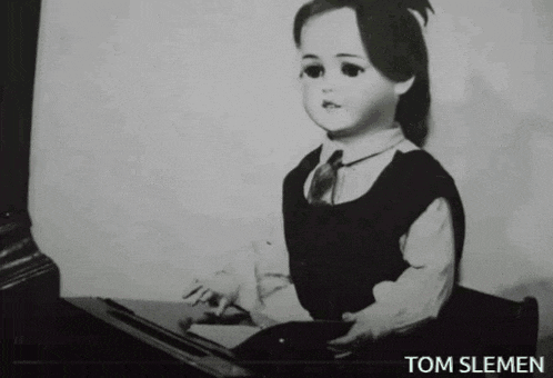 a black and white photo of a doll with the name tom slemen underneath it