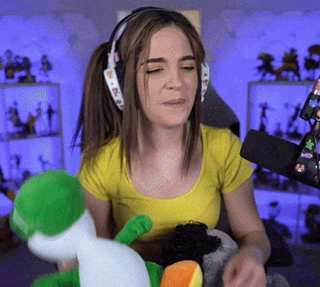 a woman wearing headphones holds a stuffed animal in her lap