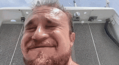 a man with a beard is making a funny face in front of a striped wall