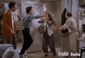 a group of people are dancing in a living room while two men are fighting each other .