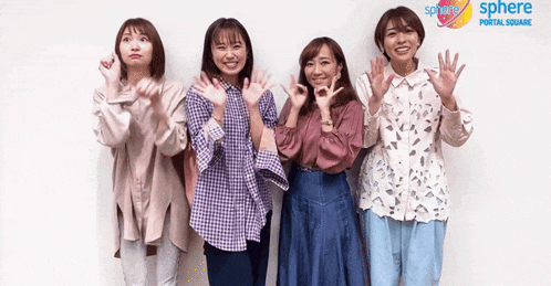 four women are posing for a picture in front of a sphere portal square sign