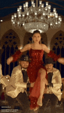 a woman in a red dress is being lifted by two men in suits