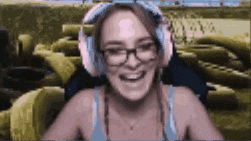 a woman wearing headphones and glasses is smiling while sitting on a couch .