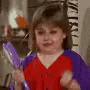 a little girl in a red and purple shirt is standing in a room holding a purple object .