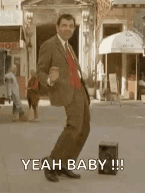 a man in a suit and tie is dancing on a street .