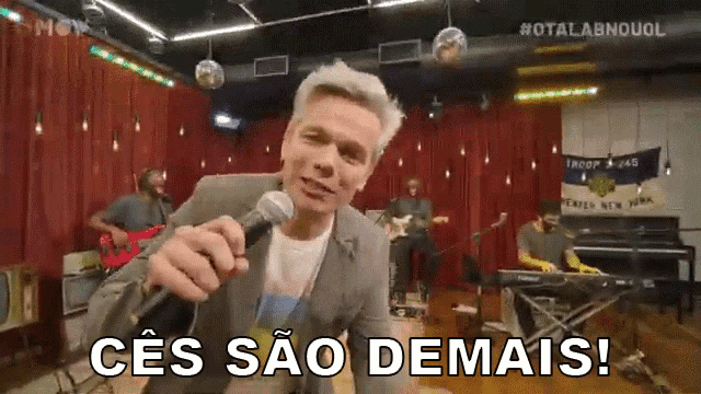 a man singing into a microphone with the words " ces sao demais " written below him