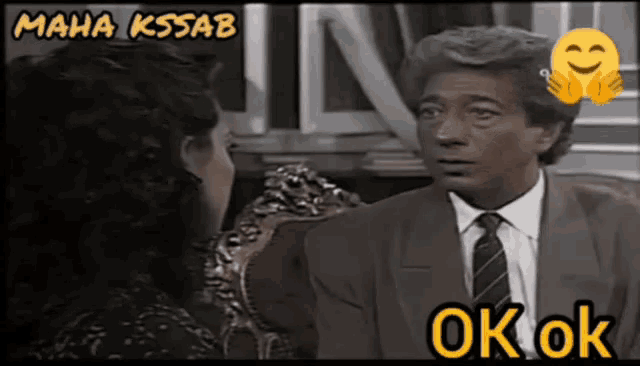 a man in a suit and tie is talking to a woman who is laughing