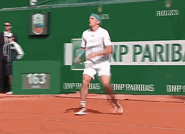 a man playing tennis in front of a bnp pariba sign