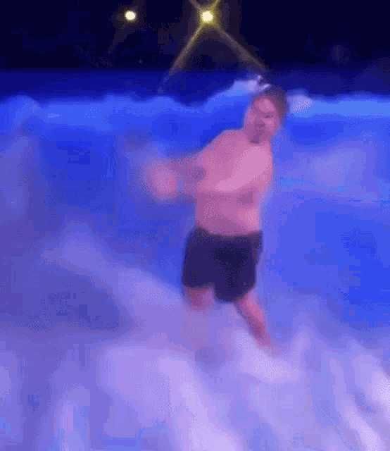 a man is standing in a swimming pool with foam coming out of the water .