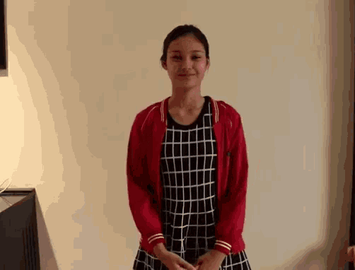 a girl wearing a red jacket and a plaid dress